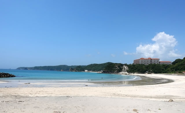 下田の多々戸浜の白い砂浜とエメラルドグリーンの海、遠くに見えるホテル