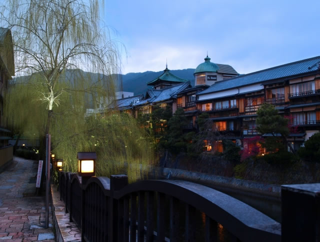 夕暮れの川沿いに並ぶ温泉旅館と情緒ある街並みの風景