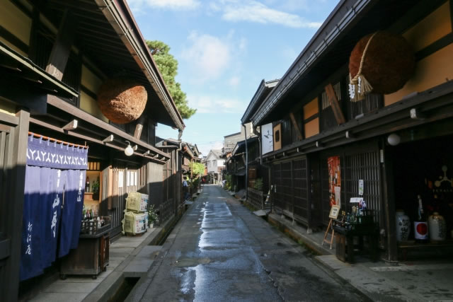 飛騨高山の古い町並みに立ち並ぶ酒蔵と杉玉が下がる通りの風景