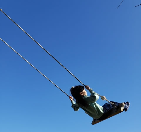 ACAO FORESTの空飛ぶブランコで青空を背景に楽しむ女性